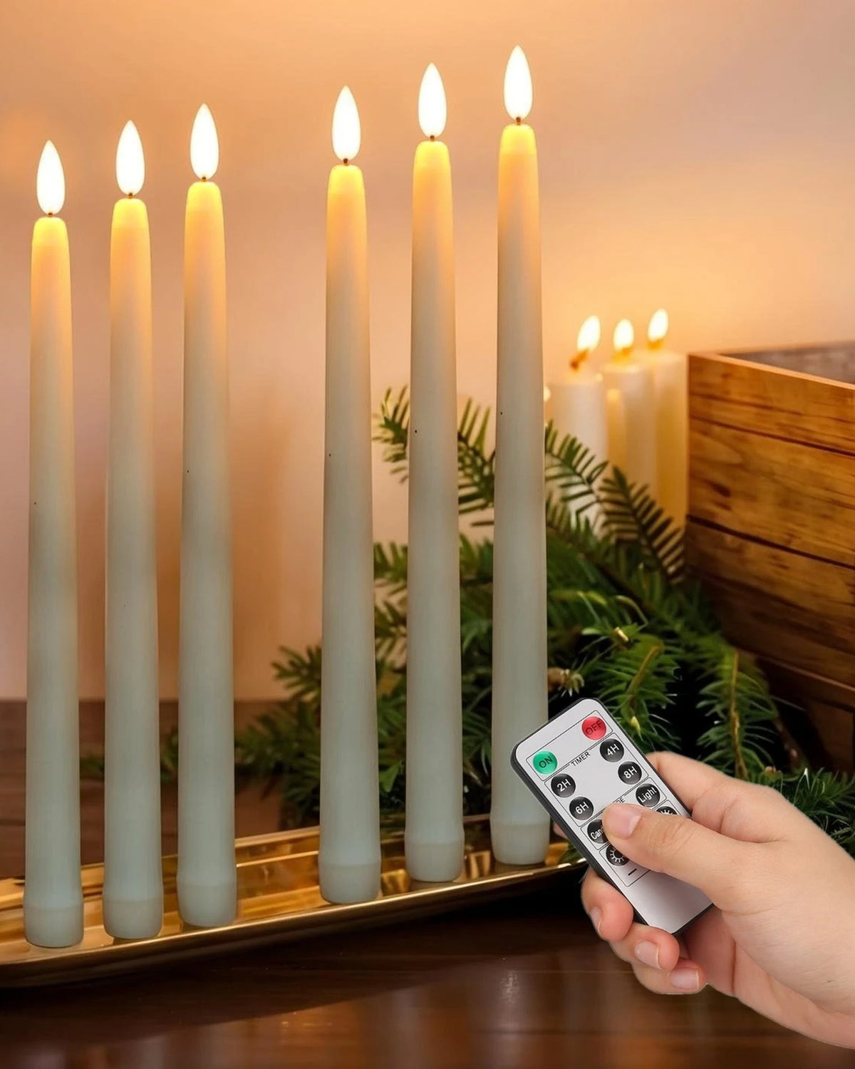 Six ivory flameless taper candles glowing on a brass tray with a remote